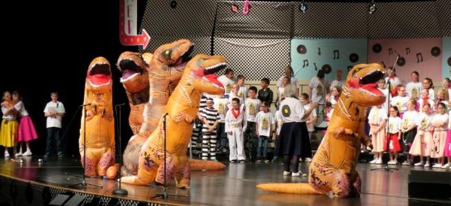 Dinosauers on stage in the 4th grade concert